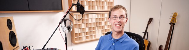 Florian Schmitz sitzt am Studio-Tisch und lächelt in die Kamera.